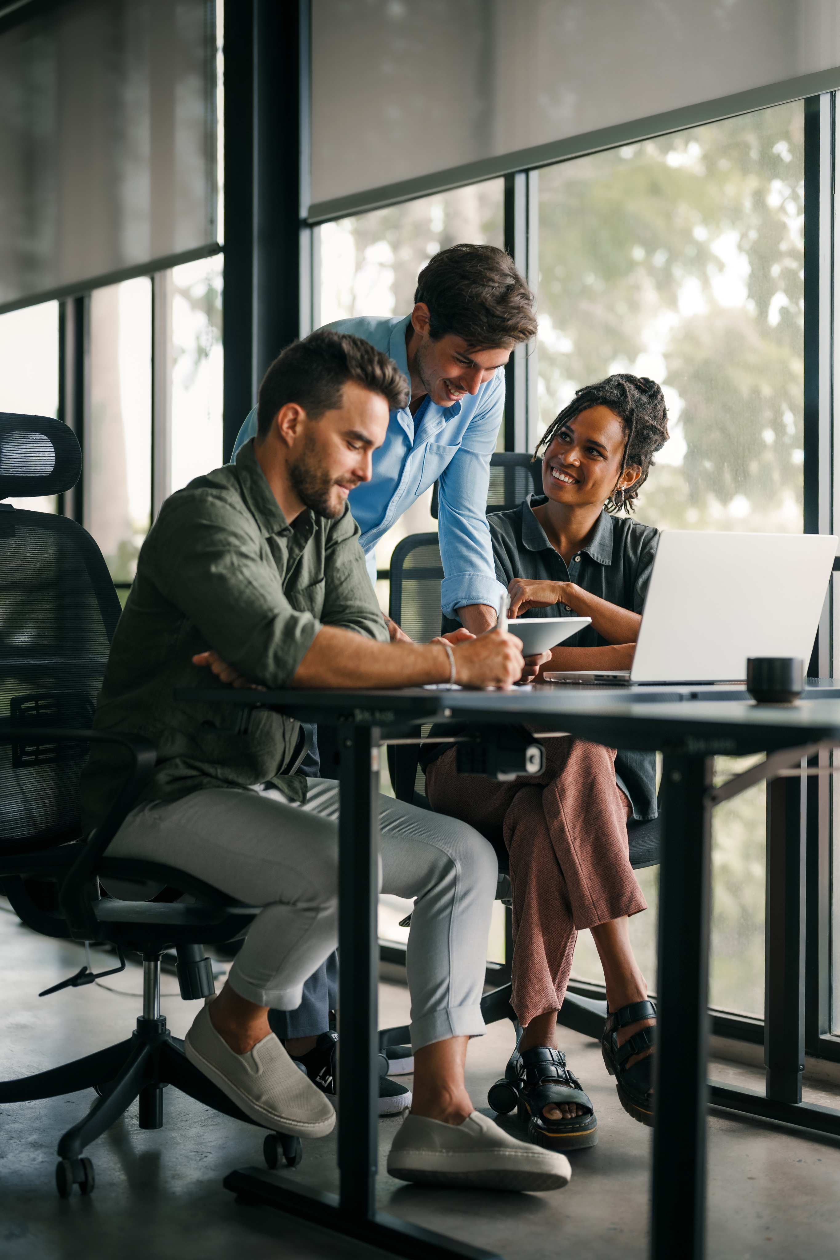Colleagues collaborating around a laptop in a bright office